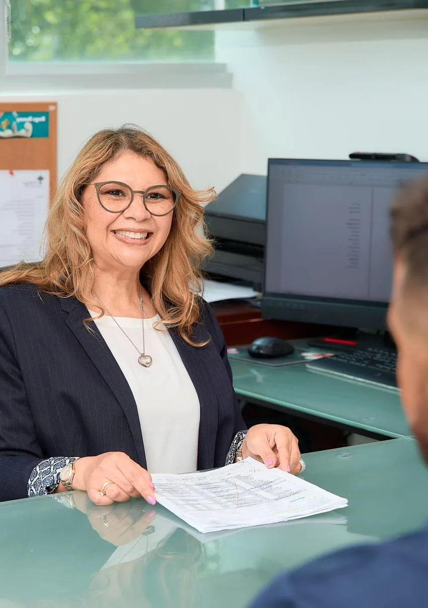 Una integrante del equipo administrativo revisa documentos con un paciente